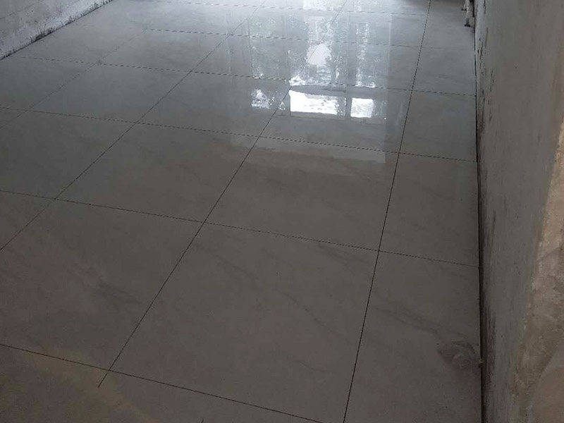 客廳地磚鋪貼裝修：首先將沙子和水泥按照3：1的比例混合后兌少量的水，使水泥和沙子混合到可以用手攥成團(tuán)的黏稠度；接著在鋪磚之前先將要鋪的地方用水潑濕。將開(kāi)始和好的水泥和沙子鏟到你要鋪瓷磚的地方，鏟完以后用小鏟子初步抹平。然后瓷磚背后抹上開(kāi)始和好的那盆比較稠的水泥漿，再將抹好水泥的磚小心平放到要鋪的地方，注意對(duì)縫。再用橡膠小榔頭敲實(shí)，用水平尺找平。最后在側(cè)邊用小榔頭的把手堵嚴(yán)實(shí)，完工。