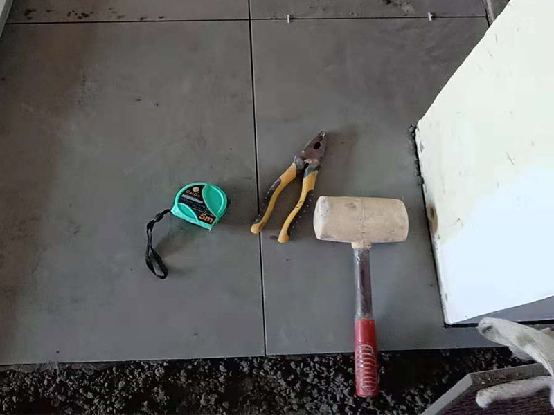 客廳地磚鋪貼：鋪貼的工具包括橡膠錘和粘結(jié)劑。在進(jìn)行施工之前先把所需要的這些材料都整理好放在一旁備用；基層的處理工作對瓷磚的平整度有很大的影響，對于基層要做好清潔工作，還有找平工作。放樣：在進(jìn)行瓷磚的鋪貼工作之前還事先找好垂直線，這樣可以在鋪貼的時(shí)候找到瓷磚的水平線，讓瓷磚鋪貼的更加的平整。粘結(jié)劑加水?dāng)嚢杈鶆?，靜置10分鐘之后就可以使用。將瓷磚表面的浮灰清除，再在瓷磚背面均勻的涂抹上粘結(jié)劑，按照預(yù)鋪的順序?qū)⒋纱u鋪貼在地面上，最后用橡膠錘輕輕拍打至服帖齊整。