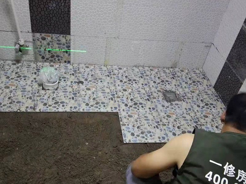 衛(wèi)生間地面花磚鋪貼:找平，就是在鋪仿古磚前，對鋪貼物表面進行處理，如地面、內(nèi)墻面、外墻面等，消除表面附著的污物，并灑水進行滋潤，然后用水泥沙混合找平，通常使用灰鏟在表面不停的涂抹使水泥地面保持大致水平，一定要等到水泥沙混合物完全干爽后再行鋪貼。用一段較長的細線，根據(jù)確定的鋪貼方式，在線上涂上顏色或白灰，然后在找平的地面上畫出仿古磚的位置及磚縫的參考線。 將亞光磚置入清水中浸泡，使瓷磚充分吸收水分，以不冒出氣泡為準，防止干燥瓷磚在裝修完成后再次吸水而導(dǎo)致磚體變形。取出浸泡好的瓷磚，抹干水漬，在找平層上噴灑足夠的水，然后在磚背面均勻抹上水泥沙漿，沙漿厚度5~6cm為宜，鋪貼大規(guī)格亞光磚時適當加厚；隨即將磚貼上，用木錘輕輕拍牢平整，避免空鼓，并隨時用直尺找平。