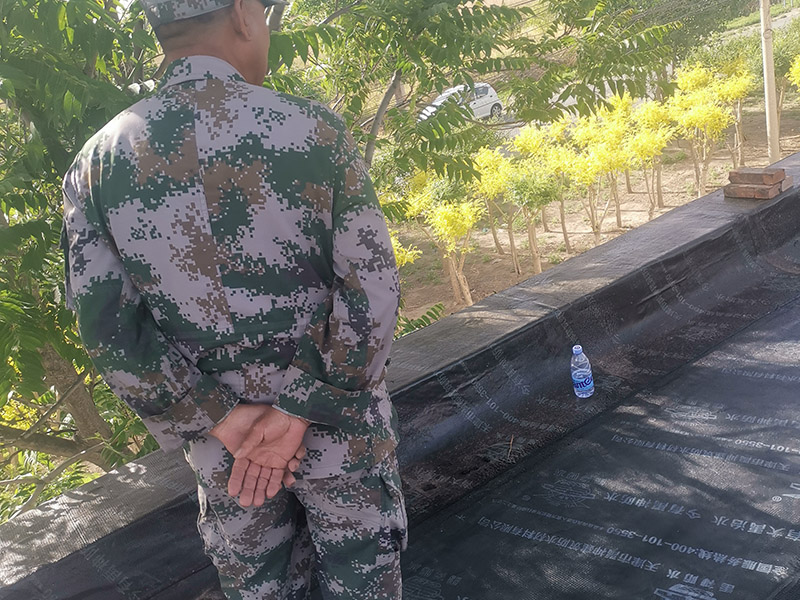 屋頂防水卷材鋪貼:清除基層表面雜物、油污、砂子，凸出表面的石子、砂漿疙瘩等應清理干凈，清掃工作必須在施工中隨時進行，并修補平整表面。尤其鏟除排水口、煙囪、管壁上的水泥砂漿等附著物；根據(jù)施工現(xiàn)場狀況，進行合理定位，確定卷材鋪貼方向，在基層上彈好卷材控制線，依循流水方向從低往高進行卷材試鋪。卷材試鋪后，先將要鋪貼的卷材剪好，反鋪于基面上(即是底部隔離紙朝上)，撕剝?nèi)ゾ聿母綦x紙。撕剝時，已剝開的隔離紙宜與粘結(jié)面保持45～60度的銳角，防止拉斷隔離紙，盡量保持在自然松弛狀態(tài)，但不要有皺折。