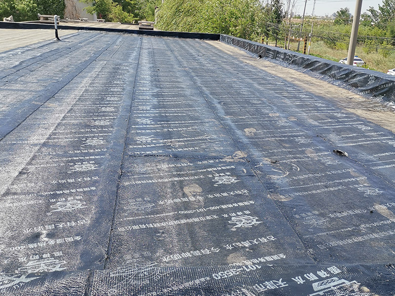 屋頂防水卷材鋪貼:清除基層表面雜物、油污、砂子，凸出表面的石子、砂漿疙瘩等應清理干凈，清掃工作必須在施工中隨時進行，并修補平整表面。尤其鏟除排水口、煙囪、管壁上的水泥砂漿等附著物；根據(jù)施工現(xiàn)場狀況，進行合理定位，確定卷材鋪貼方向，在基層上彈好卷材控制線，依循流水方向從低往高進行卷材試鋪。卷材試鋪后，先將要鋪貼的卷材剪好，反鋪于基面上(即是底部隔離紙朝上)，撕剝?nèi)ゾ聿母綦x紙。撕剝時，已剝開的隔離紙宜與粘結(jié)面保持45～60度的銳角，防止拉斷隔離紙，盡量保持在自然松弛狀態(tài)，但不要有皺折。