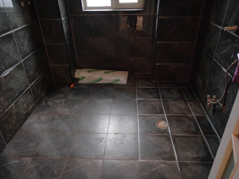 衛(wèi)生間美縫施工：使用用開槽器/平口螺絲刀/勾縫刀，清理瓷磚縫隙內(nèi)灰塵及垃圾，這一步需要力度適中，不要用蠻力，不然可能存在崩壞瓷磚的風(fēng)險(xiǎn)。然后用吸塵器，掃把或者抹布清理干凈。，建議縫隙在1.5到2mm深度合適?？p隙清理干凈后， 擰開管蓋裝上混合管，管頭卡在膠槍的卡口上。裝好混合管后，從下方用美工刀斜切45度角，切記開口要比瓷磚縫隙小，如果本身瓷磚縫隙比較小，可以不用切膠嘴。首先打出30-40CM美縫劑余料，然后沿著瓷磚縫隙開始施工，在施工的時(shí)候一定要美縫劑填充滿瓷磚縫隙，不然后續(xù)可能會發(fā)生塌陷。瓷磚縫隙打膠方法先豎后橫，沿著縫隙均勻打出美縫劑.一般有些師傅打出3-5米時(shí)停下，開始用壓邊球壓縫，十字交叉口處多壓幾次，這樣會很美觀。壓縫的工具比較多，可用刮板或者壓縫 鋼球、手指套沿著縫隙壓出 U型面就可以了