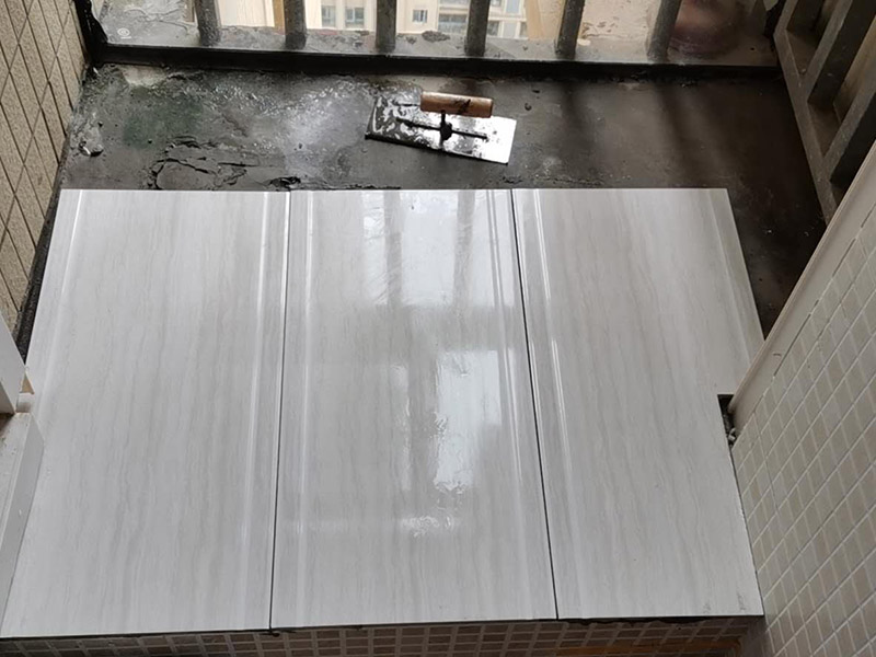 陽臺瓷磚鋪貼：準(zhǔn)備粘結(jié)劑前，瓷磚不應(yīng)浸水，但要用鋼絲刷除去磚背面的松散物質(zhì)，并用濕布抹去磚背的浮塵。然后按照生產(chǎn)商建議的比例將水或乳液放到攪拌桶中攪拌直至粘結(jié)劑均勻無結(jié)塊。初始攪拌后的粘結(jié)劑應(yīng)靜置在攪拌桶中，直到生產(chǎn)商推薦的熟化時間過后攪拌一下再使用。 在鋪壓瓷磚前，在瓷磚背面也批一薄層粘結(jié)劑。這種雙批法雖然用的材料和工時比較多，但卻能夠保證粘貼的質(zhì)量和耐久性。 在粘結(jié)劑量置晾時間內(nèi)，將準(zhǔn)備好的瓷磚鋪壓到位，垂直于梳理方向輕微搓動以排出磚下的空氣。鋪貼到位后用橡皮錘輕擊，用尺寸合適的十字定位架來調(diào)整表面平整度及接縫的平直。