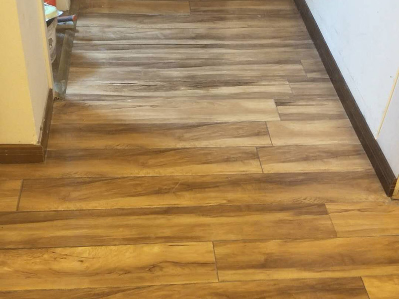 入戶門鋪地板：1、先對地面進行找平，水平的誤差不能超過2毫米。地面要是不平，腳感就不好。再就是將邊、角部位等突起或有不平的地方進行局部修整。再鋪防潮層，防潮層可以防止以后地板受潮。鋪平，接縫處要并攏。  2、然后就是安裝地板了，因為地板是要錯落安裝的，先預(yù)鋪一下，將部分地板一分為二，要按尺寸來鋸，萬一鋸多了，地板損耗就大了。因為地板有一定的膨脹率，因此鋪裝前要在其與墻面接觸的部位預(yù)留膨脹縫，以免地板起鼓。膨脹縫的大小一般和地板的膨脹系數(shù)有關(guān)系。粘合地板的膠水要用強化地板專用的，這種膠的污染比較小。不要隨便在市場上選非地板專用膠，地板本身就存在的污染上再增加污染源。  3、鋪前看好地板是否用對，再鋪設(shè)地板。在鋪設(shè)時，要一塊短的旁邊鋪一塊長的，這樣交叉鋪設(shè)地板就咬得住不易松動，地板拼合后還要用工具敲緊。再下來就是銜接了，一般用地板壓條掩蓋。但也有用玻璃膠填充。