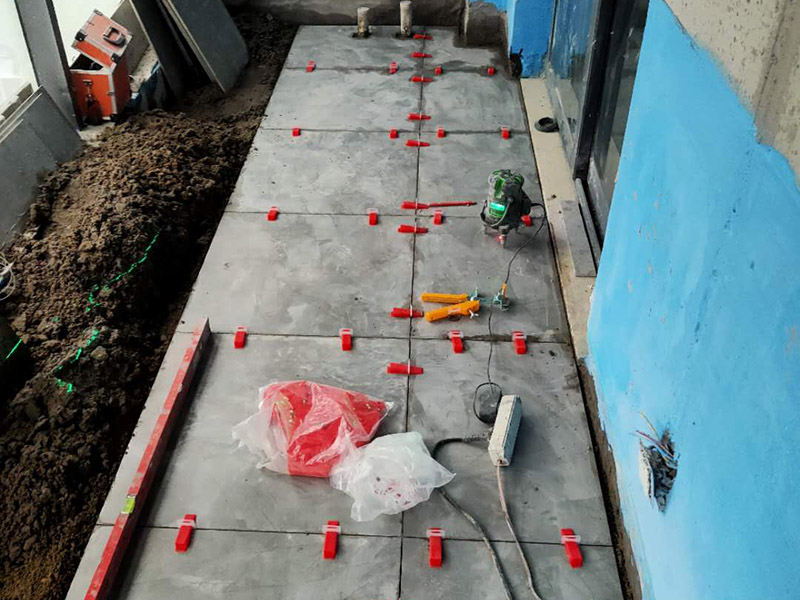 陽臺防水貼磚:在粘結(jié)劑量置晾時間內(nèi)，將準備好的瓷磚鋪壓到位，垂直于梳理方向輕微搓動以排出磚下的空氣。鋪貼到位后用橡皮錘輕擊，用尺寸合適的十字定位架來調(diào)整表面平整度及接縫的平直。鋪設好的磚面應該及時清理干凈，特別是去除殘留其上的粘結(jié)劑。合格的粘結(jié)劑干硬后即使在陶瓷磚面上也不易被清除掉。清理好的瓷磚面應該立即擺放標識進行隔離，避免污染或擾動，直到下一個填縫工序。