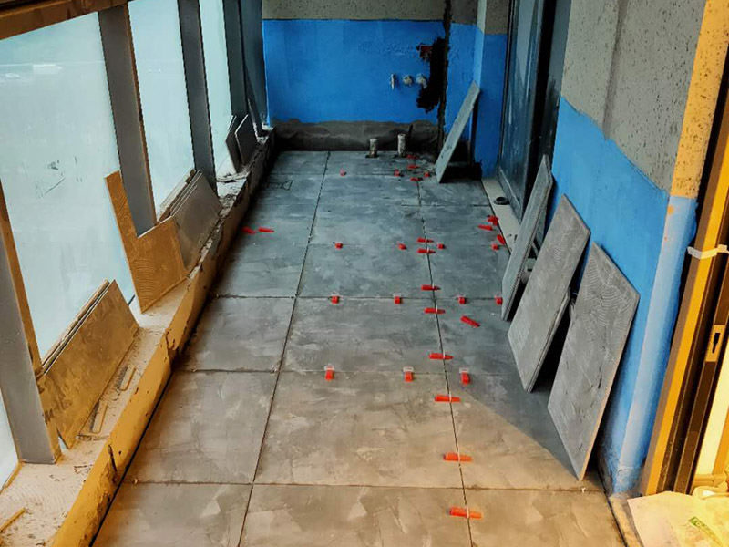 陽臺防水貼磚:在粘結(jié)劑量置晾時間內(nèi)，將準備好的瓷磚鋪壓到位，垂直于梳理方向輕微搓動以排出磚下的空氣。鋪貼到位后用橡皮錘輕擊，用尺寸合適的十字定位架來調(diào)整表面平整度及接縫的平直。鋪設好的磚面應該及時清理干凈，特別是去除殘留其上的粘結(jié)劑。合格的粘結(jié)劑干硬后即使在陶瓷磚面上也不易被清除掉。清理好的瓷磚面應該立即擺放標識進行隔離，避免污染或擾動，直到下一個填縫工序。