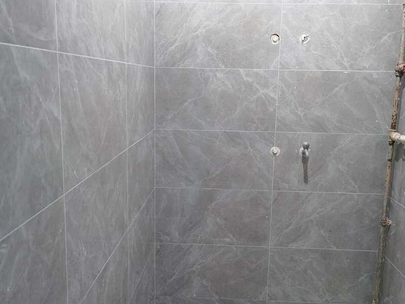 衛(wèi)生間貼磚施工：應(yīng)全部清理墻面上的各類污物，打掃干凈現(xiàn)場，特別是腳落里。用泥刀先批墻，后用水泥漿找平。這個工序很重要，確保底子平，防止貼后空鼓。墻面要刷防水涂料，防止貼后浸水，一般高度不低于1.8米，刷的時候會稍高一些。根據(jù)設(shè)計鋪貼圖樣的要求，確定排磚方案，用墨斗彈線，以減少施工損耗。把剛剛攪拌好的粘結(jié)劑漿料均勻的刮到墻上。瓷磚上墻將經(jīng)過預(yù)先清潔的瓷磚平整地鋪貼在粘結(jié)劑漿料基層上，使用橡膠錘將瓷磚拍實鋪平。施工過程中，可小幅度轉(zhuǎn)動瓷磚，使?jié){料與瓷磚背面充分接觸。專家建議在鋪貼時，隨機取下已鋪貼于基層上的瓷磚作檢查。確保漿料與瓷磚背面的充分接觸。 留縫大小調(diào)整根據(jù)瓷磚的尺寸，在磚與磚之間預(yù)留相應(yīng)尺寸的縫隙留待嵌縫?？捎醚篮灥认裙潭ǎ辰Y(jié)劑具有一定的可調(diào)整性，可對留縫的大小進行調(diào)整。