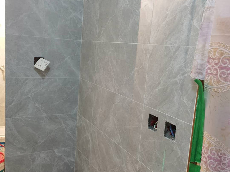 衛(wèi)生間貼磚施工：應(yīng)全部清理墻面上的各類污物，打掃干凈現(xiàn)場，特別是腳落里。用泥刀先批墻，后用水泥漿找平。這個工序很重要，確保底子平，防止貼后空鼓。墻面要刷防水涂料，防止貼后浸水，一般高度不低于1.8米，刷的時候會稍高一些。根據(jù)設(shè)計鋪貼圖樣的要求，確定排磚方案，用墨斗彈線，以減少施工損耗。把剛剛攪拌好的粘結(jié)劑漿料均勻的刮到墻上。瓷磚上墻將經(jīng)過預(yù)先清潔的瓷磚平整地鋪貼在粘結(jié)劑漿料基層上，使用橡膠錘將瓷磚拍實鋪平。施工過程中，可小幅度轉(zhuǎn)動瓷磚，使?jié){料與瓷磚背面充分接觸。專家建議在鋪貼時，隨機取下已鋪貼于基層上的瓷磚作檢查。確保漿料與瓷磚背面的充分接觸。 留縫大小調(diào)整根據(jù)瓷磚的尺寸，在磚與磚之間預(yù)留相應(yīng)尺寸的縫隙留待嵌縫?？捎醚篮灥认裙潭?，粘結(jié)劑具有一定的可調(diào)整性，可對留縫的大小進行調(diào)整。