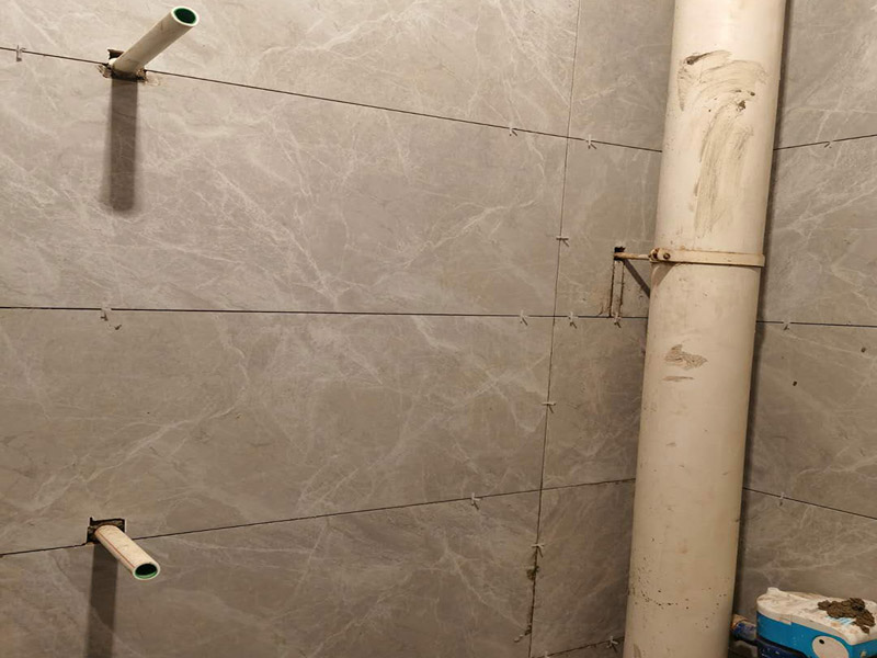 衛(wèi)生間貼磚施工：應(yīng)全部清理墻面上的各類污物，打掃干凈現(xiàn)場，特別是腳落里。用泥刀先批墻，后用水泥漿找平。這個工序很重要，確保底子平，防止貼后空鼓。墻面要刷防水涂料，防止貼后浸水，一般高度不低于1.8米，刷的時候會稍高一些。根據(jù)設(shè)計鋪貼圖樣的要求，確定排磚方案，用墨斗彈線，以減少施工損耗。把剛剛攪拌好的粘結(jié)劑漿料均勻的刮到墻上。瓷磚上墻將經(jīng)過預(yù)先清潔的瓷磚平整地鋪貼在粘結(jié)劑漿料基層上，使用橡膠錘將瓷磚拍實鋪平。施工過程中，可小幅度轉(zhuǎn)動瓷磚，使?jié){料與瓷磚背面充分接觸。專家建議在鋪貼時，隨機取下已鋪貼于基層上的瓷磚作檢查。確保漿料與瓷磚背面的充分接觸。 留縫大小調(diào)整根據(jù)瓷磚的尺寸，在磚與磚之間預(yù)留相應(yīng)尺寸的縫隙留待嵌縫。可用牙簽等先固定，粘結(jié)劑具有一定的可調(diào)整性，可對留縫的大小進行調(diào)整。