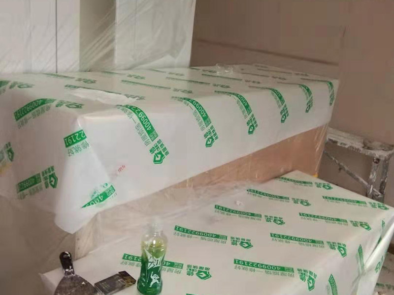 全屋家具成品保護：滿鋪成品瓦楞紙板，再用干凈彩條布滿鋪在普通石膏板上，在彩條布交接處及轉(zhuǎn)角處用膠帶固定，也可選用木芯板或三夾板。材料選用視上人、車情況而定。 所有成品飾面板在安裝好后必須用PE保護膜覆蓋包起來，所有成品飾面板的陽角位必須用硬質(zhì)紙護角或泡沫棉進行保護性包裝，防止交被其他施工人員碰撞。 1、入戶門扇用公司統(tǒng)一的門貼進行全面包裹保護，用透明膠帶將保護膜粘貼牢固平整。 2、用標準保護膜將門框三面保護完整并固定牢固。 3、工程完工后拆除保護膜時如果有粘貼時的膠痕，應用酒精或?qū)Ｓ玫那逦蹌┣宄z痕。