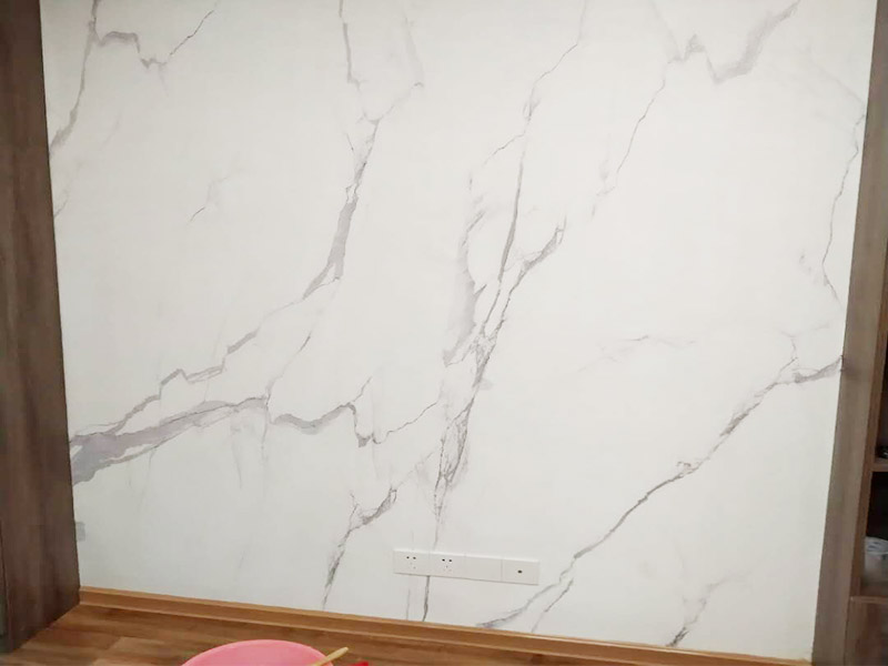 電視背景墻裝修：首先需要量背景墻的尺寸，然后記錄下來，可以去網(wǎng)上或者實體店購買墻布。要注意尺寸要留有余地，才能進(jìn)行處理。要對貼墻布的墻面先進(jìn)行處理，墻面如果是剛做好的水泥漆，干了就可以操作。如果是普通的墻面，需要先做基膜。把購買來的墻布展開，然后站到梯椅上，把墻布對角貼上去。要注意張貼的平整，不能一邊高一邊低。用手按壓住墻布，然后用刮片把墻布刮平。刮角落的時候，要注意用力刮平，不要有褶皺或者翹角。墻布刮好后，要用鋒利的刀片，進(jìn)行修邊處理，電線孔也要用刀片割開。修邊好后，也要用刮片再刮一遍。裁剪邊框的墻紙，按照同樣步驟張貼。張貼好后，用布擦一下，防止膠水沾住。查看張貼效果，關(guān)上窗戶。