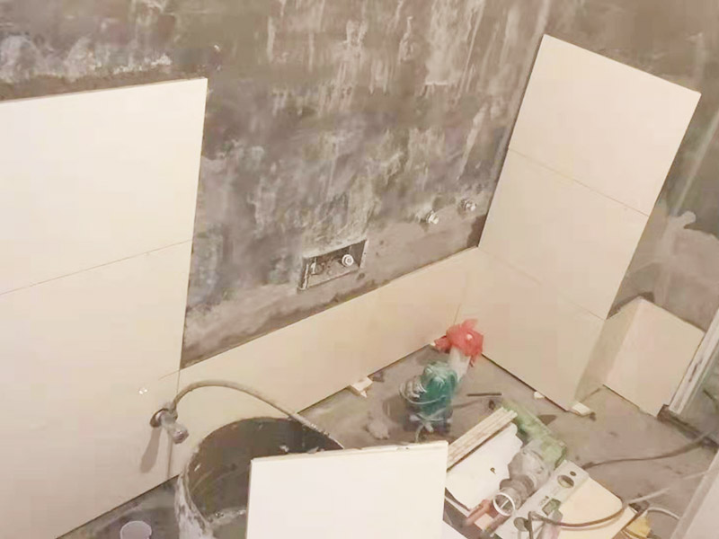 衛(wèi)生間墻面貼磚：首先應(yīng)除去基層表面的污垢，油漬，浮灰;除去基層上所有涂料層，膩子層;如果基層未能達到平整度要求，需對基層進行預(yù)先的找平處理。鋪貼瓷磚前需事先找好垂直線，以此為基準鋪貼的瓷磚高低均勻、垂直美觀;此外，施工前在墻體四周需彈出標高控制線，在地面彈出十字線，以控制地磚分隔尺寸。對瓷磚的色彩、紋理、表面平整等進行嚴格的挑選，然后按照圖紙要求預(yù)鋪。對可能出現(xiàn)的尺寸、色彩、紋理誤差等進行調(diào)整、交換，直至達到最佳效果。 調(diào)制粘結(jié)劑：加水后將粘結(jié)劑漿料攪拌至潤滑均勻，無明顯塊狀或糊狀結(jié)塊，攪拌后的漿料靜置5-10分鐘后再稍加攪拌1-2分鐘即可使用。 將瓷磚平整地鋪貼在基層上，使用橡膠錘將瓷磚拍實鋪平。施工過程中，可小幅度轉(zhuǎn)動瓷磚，使?jié){料與瓷磚背面充分接觸。