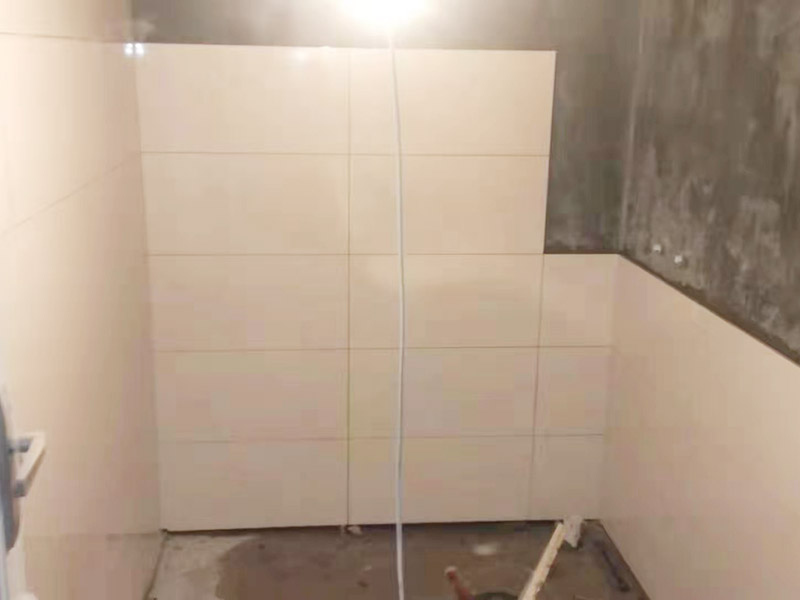 衛(wèi)生間墻面貼磚：首先應(yīng)除去基層表面的污垢，油漬，浮灰;除去基層上所有涂料層，膩子層;如果基層未能達到平整度要求，需對基層進行預(yù)先的找平處理。鋪貼瓷磚前需事先找好垂直線，以此為基準鋪貼的瓷磚高低均勻、垂直美觀;此外，施工前在墻體四周需彈出標高控制線，在地面彈出十字線，以控制地磚分隔尺寸。對瓷磚的色彩、紋理、表面平整等進行嚴格的挑選，然后按照圖紙要求預(yù)鋪。對可能出現(xiàn)的尺寸、色彩、紋理誤差等進行調(diào)整、交換，直至達到最佳效果。 調(diào)制粘結(jié)劑：加水后將粘結(jié)劑漿料攪拌至潤滑均勻，無明顯塊狀或糊狀結(jié)塊，攪拌后的漿料靜置5-10分鐘后再稍加攪拌1-2分鐘即可使用。 將瓷磚平整地鋪貼在基層上，使用橡膠錘將瓷磚拍實鋪平。施工過程中，可小幅度轉(zhuǎn)動瓷磚，使?jié){料與瓷磚背面充分接觸。