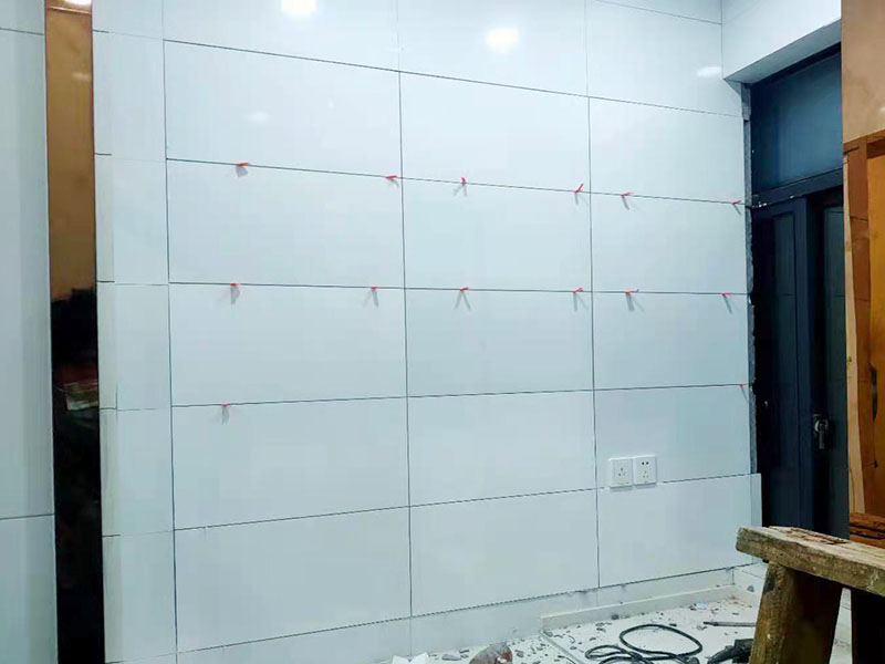 墻磚鋪貼施工：基層處理：保持墻面的平滑，踢平表面凹凸不平的位置或用1:3比例的水泥漿抹平，用鐵絲擦掉殘留的灰塵、油漬、砂漿等。 找標(biāo)高、彈線：根據(jù)水平控制線和設(shè)計(jì)圖紙劃出標(biāo)高，再拋出十字線并保持墻面一線和地面一線垂直。 預(yù)鋪：在圖紙?jiān)O(shè)計(jì)要求的基礎(chǔ)上，嚴(yán)格挑選墻磚的色彩、紋理等，然后進(jìn)行預(yù)鋪，對于預(yù)鋪效果中可能出現(xiàn)的紋理、尺寸、色差進(jìn)行調(diào)整、更換，直到達(dá)到最佳效果。 貼磚：貼磚選用1：3比例的干硬性水泥砂漿，砂漿厚度2cm左右。鋪貼前將墻磚背面濕潤，正面保持干燥。把墻磚輕輕地放在水泥砂漿上，用手錘輕敲瓷磚表面直至緊密平整即可。 勾縫、擦縫：在貼完磚24小時(shí)后進(jìn)行勾縫工作，采用同一品種的水泥漿或?qū)Ｓ锰羁p劑進(jìn)行空隙填補(bǔ)，使墻磚最終緊密嚴(yán)實(shí)，最后再擦凈多余的水泥或填縫劑。