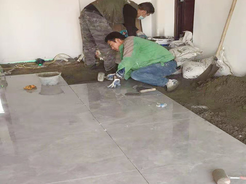 客廳地面貼磚：首先要把基層用水澆濕，除去雜物和浮沙。再抹結(jié)合層，需要注意的是要使用1：3的干性水泥漿，按照水平線探鋪平整，然后再把磚放在沙漿上用膠皮錘振實(shí)。這時(shí)再把地面磚取下澆抹水泥漿，然后把地面磚放實(shí)振平就可以了。采用干鋪法可以有效地避免鋪裝過程中造成的空鼓、氣泡等現(xiàn)象發(fā)生。但是干鋪法的技術(shù)含量比較高，所以費(fèi)用也會(huì)比較貴。