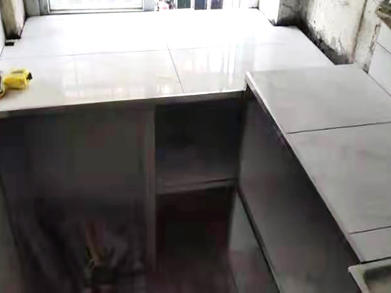 廚房磚砌櫥柜：櫥柜的水電定位時(shí)，先劃分功能區(qū)：洗菜盆區(qū)、灶臺(tái)區(qū)、切菜區(qū)、電器區(qū)，把這些區(qū)域的具體尺寸畫在墻面上，安排好進(jìn)水管、排水管和各種插座的準(zhǔn)確位置。 磚砌櫥柜制作的時(shí)候先做櫥柜的圍角，可以根據(jù)自己的喜好選擇不同顏色的瓷磚來實(shí)現(xiàn)。圍角完成以后的重要工作就是用水泥和砂漿將櫥柜的底部填實(shí)，上面鋪瓷磚。同時(shí)，瓷磚豎隔板的位置按照櫥柜圖紙進(jìn)行預(yù)留。 磚砌櫥柜制作好之后，我們可以根據(jù)自己喜歡的風(fēng)格選擇不同材質(zhì)的石材臺(tái)面和門板，完全不影響美觀，同時(shí)對(duì)于櫥柜內(nèi)部我們均采用不銹鋼條進(jìn)行收邊，既美觀又好打掃衛(wèi)生。